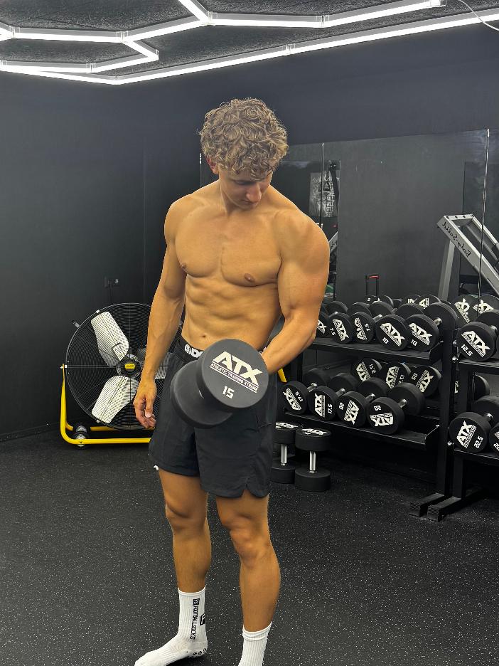 Ronan van den Berg traint met een dumbbell in zijn privégym in Den Haag